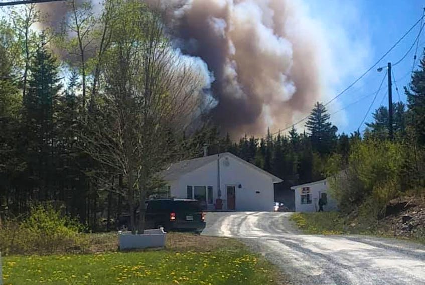 Heavy smoke from a brush fire blows behind a house near the end of Myra Road, heading toward Porters Lake, on Saturday, May 23, 2020. - Venus Yurcak