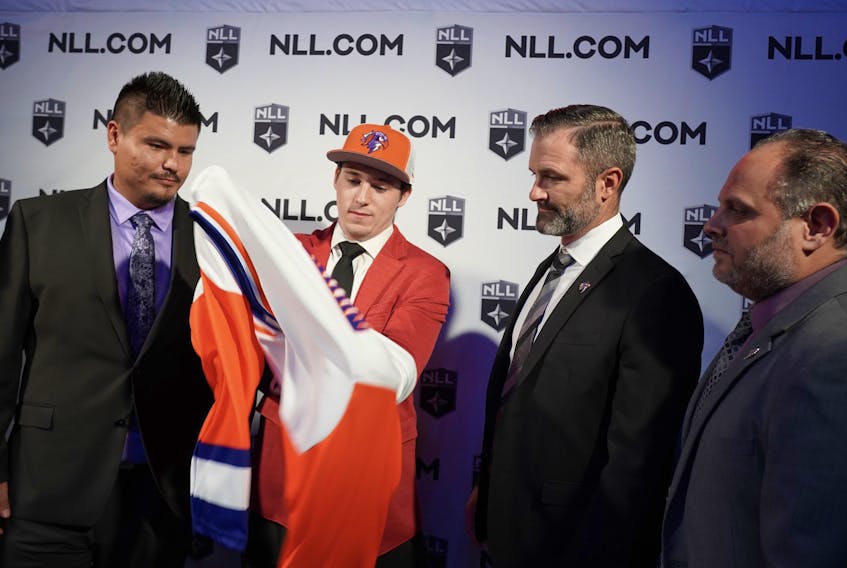Clarke Petterson puts on his uniform after being drafted fifth overall by the Halifax Thunderbirds in the National Lacrosse League draft on Tuesday night in Philadelphia. From left are: Brandon Styres, Clarke, head coach Mike Accursi and president and CEO John Catalano.