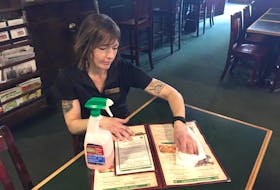 Shona Davidson of Paddy’s Pub in Kentville sanitizes a menu Monday morning. The restaurant has upped its sanitization protocols as part of increased measures around the province to combat the spread of COVID-19.