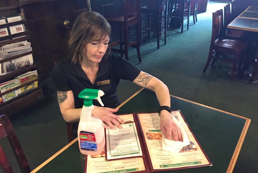 Shona Davidson of Paddy’s Pub in Kentville sanitizes a menu Monday morning. The restaurant has upped its sanitization protocols as part of increased measures around the province to combat the spread of COVID-19.