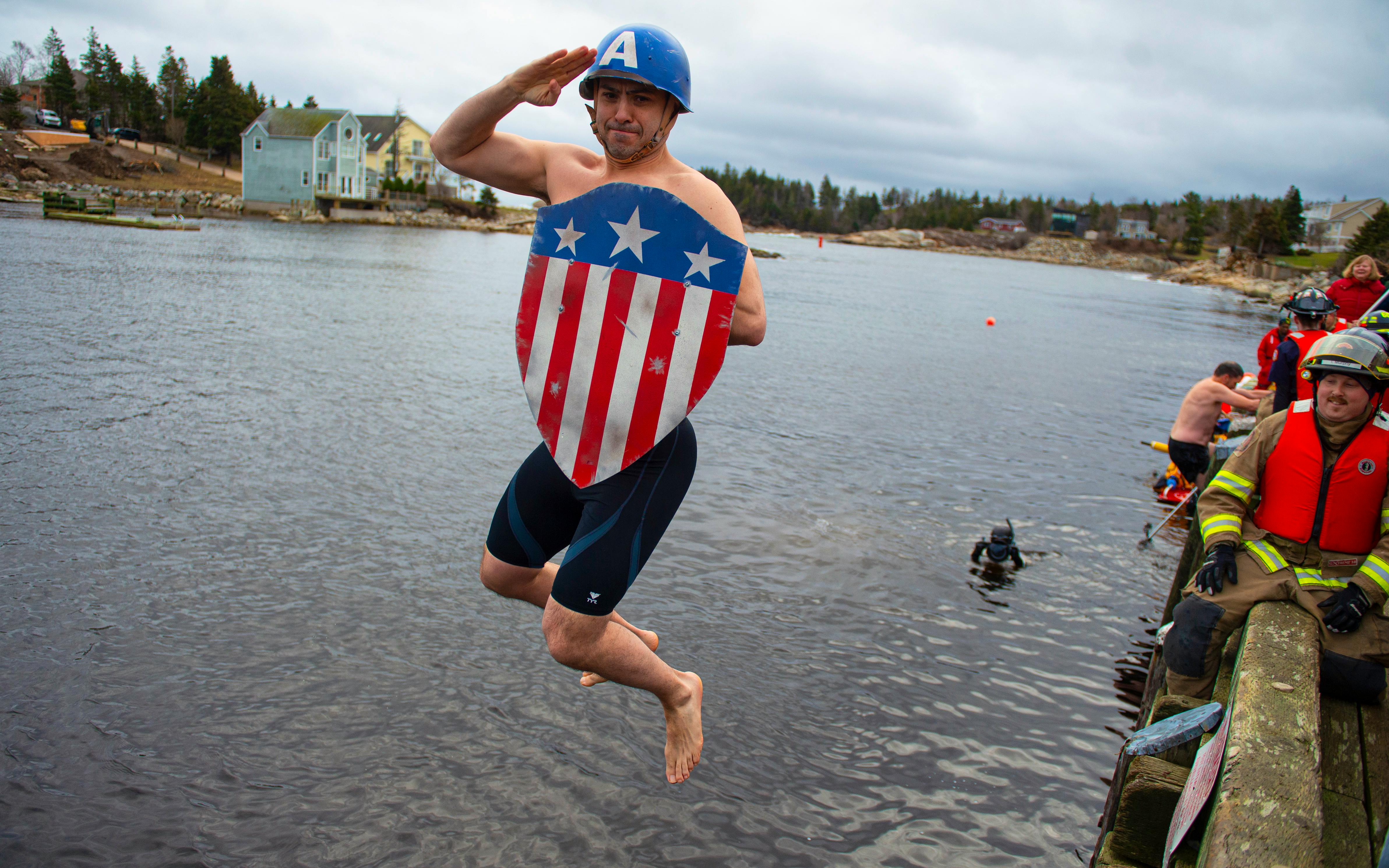 Captain America, a.k.a. Dartmouth's Andrew Maggio, salutes as he leaps into the cold water during the 26th Herring Cove Polar Bear Dip on Wednesday, January 1, 2020. This was Maggio's first time taking part in annual event and thought he might as well do it in style.