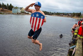Captain America, a.k.a. Dartmouth's Andrew Maggio, salutes as he leaps into the cold water during the 26th Herring Cove Polar Bear Dip on Wednesday, January 1, 2020. This was Maggio's first time taking part in annual event and thought he might as well do it in style.