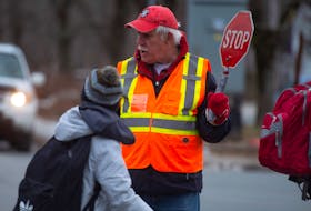 Eugene Holloway, a crossing guard since 1985, helps students cross the street at the intersection of Quinpool and Connaught on Tuesday, January 28, 2020.