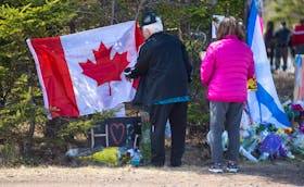 Garry Rogers and his wife Stella place a Canadian flag at a memorial at the end of Portapique Beach Road on Wednesday, April 22, 2020. Rogers lives in Truro but is originally from Cape Breton. He wanted to place the flag on behalf of the people of Cape Breton who can’t come in person to express their condolences.
