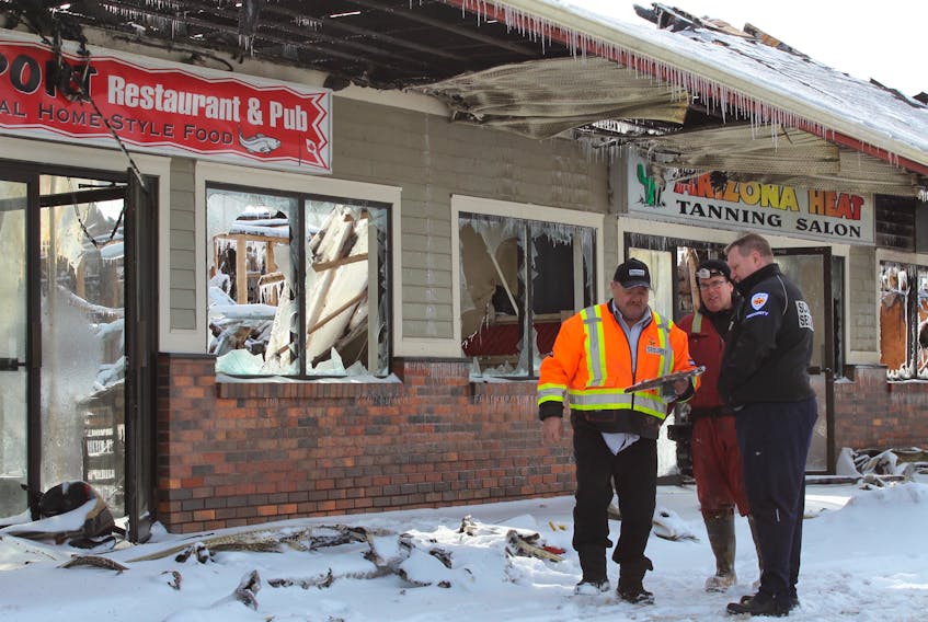 Dave Bishop of Scarlett Security (left) holds a framed photo of Boston Bruins legend Bobby Orr, which was taken from the debris inside the fire-damaged Outport Restaurant and Pub in Paradise by insurance adjuster Rick Fifield (centre) Monday afternoon, two days after the strip mall at Neil's Pond Plaza was destroyed by fire. Looking on is fellow security guard Mckinnon Clarke (right).