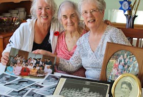 From left, Joan Byrne, Mary Keiley and Maureen Fahey of St. John’s look over graduation and reunion photos. They and many of their classmates from the St. Clare’s school of nursing are reuniting for their 60th anniversary, starting Saturday.