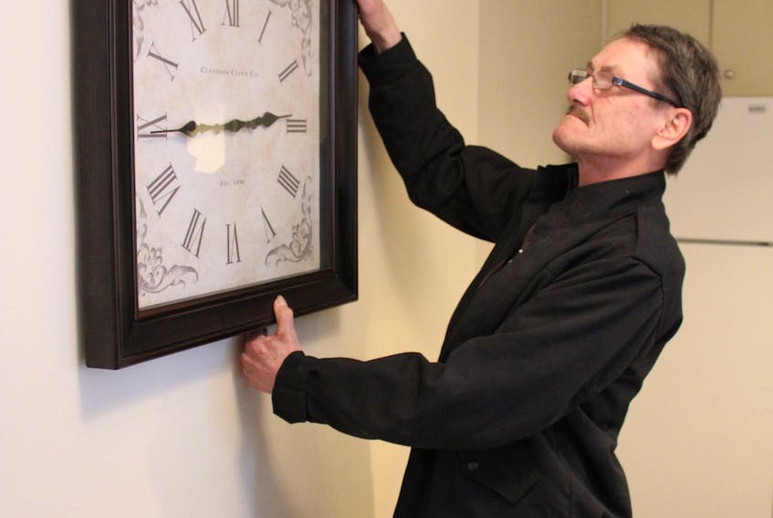Charlie Warren uses his keen eye for detail to level a clock that hangs in the kitchen of a unit that he and a group of volunteers were finalizing last week for a new client to move in to. Warren is part of a group that makes dreams happen with Right Turn Investments.