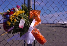 A bouquet of flowers is tied to the gates of the Cougar Helicopters facility at St. John’s International Airport on Friday, March 13, 2009, the day after Cougar Flight 491 crashed in the Atlantic Ocean, killing 17 of the 18 people on board.