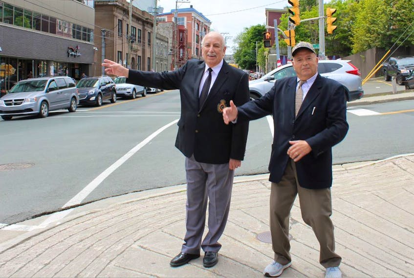 Retired RNC officers Mel Parsons (left) and Frank Miller demonstrate their traffic directing styles at the corner of Prescott Street and Duckworth Street, where the two met Friday to talk about their days as RNC traffic cops.