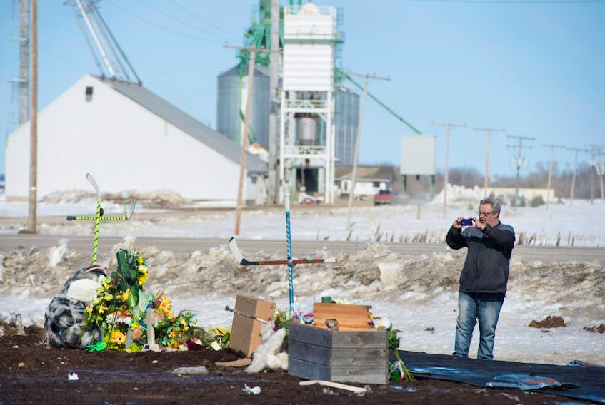 Myles Shumlanski takes a picture on April 10 of a makeshift memorial at the intersection of a fatal crash between a bus and a transport truck near Tisdale, Sask. Shumlanski’s son Nick, a player on the Humboldt Broncos Junior A hockey team, was one of the survivors of the April 6 collision.