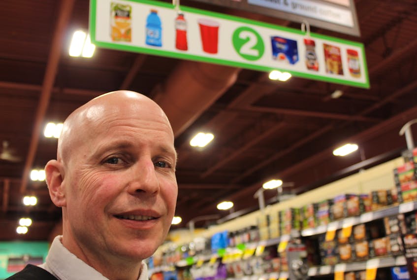 Pete Wilkins, assistant store manager at Sobeys in Paradise, stands in front of the product indicators that are found in each aisle. They are a visual aspect of the sensory-friendly hours at the grocery store.