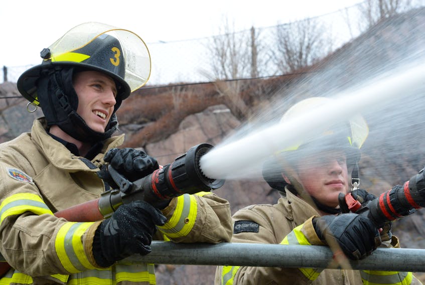 Firefighting students Justin Fowler (left) and Jonas Foley aim their hoses at a simulated structure fire in the Battery.