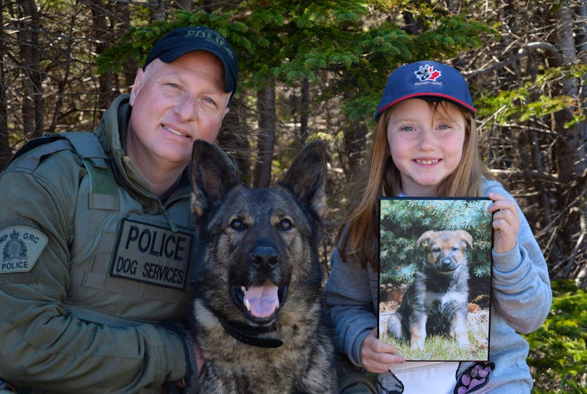 Rayanna Etheridge, 8, of Conception Bay South with RCMP police service dog Grinch and his handler Sgt. Bill Frisby on Tuesday during a presentation ceremony at Topsail Elementary School.