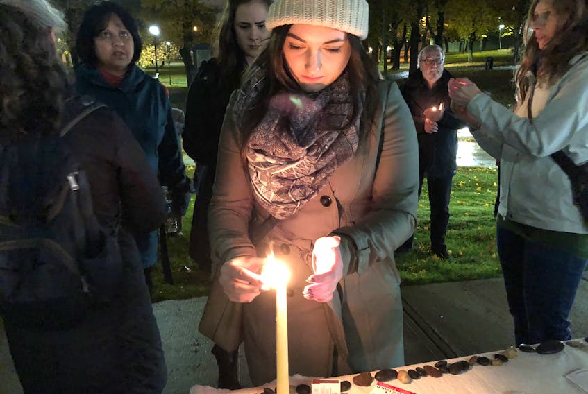 Rebecca French lights a candle at the Stronger than Hate vigil in Bannerman Park in St. John’s on Monday night.