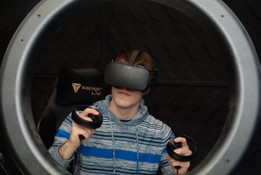 YouTuber Matt Shea wears a virtual reality headset and holds other devices for the set in his hand.