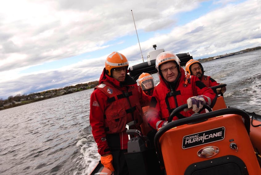 With colleagues along for the ride, Newfoundland and Labrador Senator Fabian Manning  (at wheel) drives a search and rescue Zodiac during the Senate Committee on Fisheries and Oceans fact-finding study of search and rescue operations across the country. At left is an unidentified search and rescue personnel, while behind Manning is retired Senator Elizabeth Hubley and the late Senator Tobias C. Enverga Jr. (right).