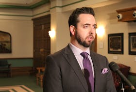 Justice Minister Andrew Parsons speaks with reporters Thursday outside the House of Assembly.