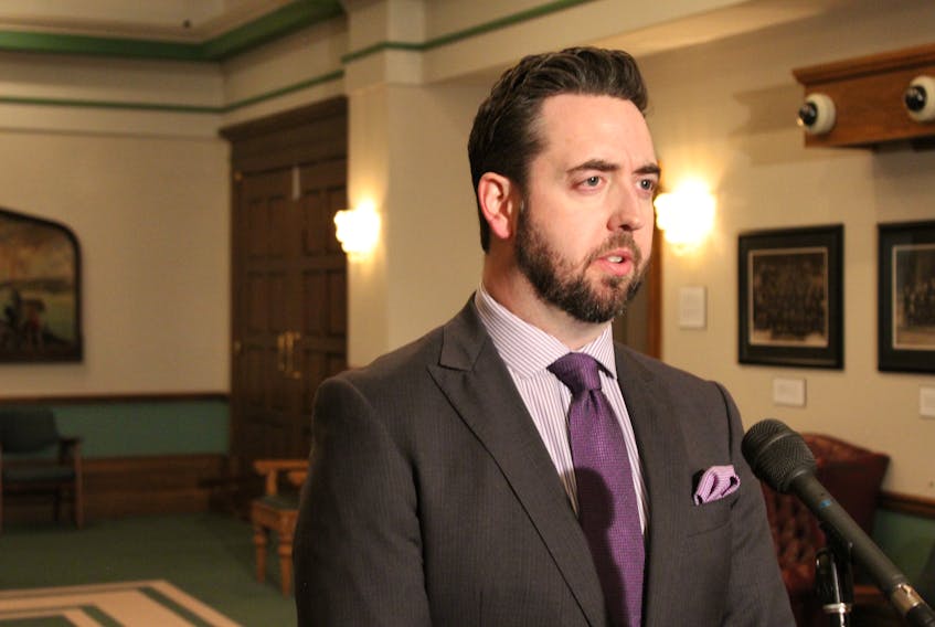 Justice Minister Andrew Parsons speaks with reporters Thursday outside the House of Assembly.