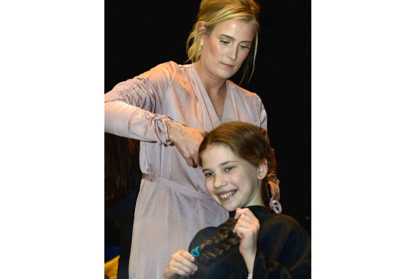 Grade 5 student Kate Rumbolt gets her four 10-inch ponytails cut by the clippers of April Gordon, a stylist at The Headroom on LeMarchant Road, Thursday at Mary Queen of Peace school.
