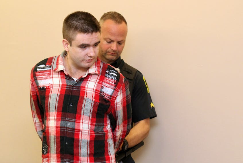 Dustin Etheridge, 26, is handcuffed by a sheriff’s officer after his conviction in provincial court in St. John’s Wednesday. Etheridge – who is already in custody on murder conspiracy charges – was sentenced to three months in jail on charges of possessing a weapon, damaging property and breaching court orders.