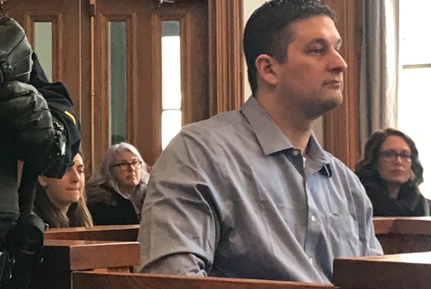 A sheriff's officer stands next to accused murderer Trent Butt as he sits in the prisoner's box awaiting the start of his trial Wednesday. Butt has admitted to causing the death of his daughter, Quinn, 5, but says he didn't plan to do it and doesn't remember it.