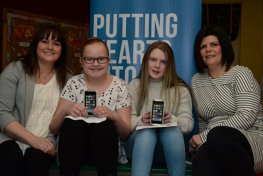 Abigail Smith, 10, and Faith Ross, 11, pupils at Holy Family School in Paradise, show mini iPads they won as runners-up in a national writing contest, the Meaning of Home, in support of Habitat for Humanity Canada. At left is Sandra Whiffen of Habitat for Humanity NL, and at right is Tonia Williams of contest sponsor Genworth Canada.