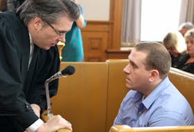 Brandon Phillips, who was convicted in December of second-degree murder in the shooting death of Larry Wellman, speaks to his lawyer, Mark Gruchy, during his sentencing hearing in St. John’s Thursday afternoon.