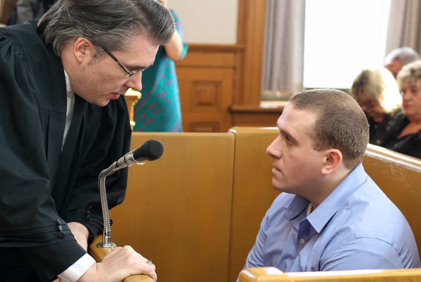 Brandon Phillips, who was convicted in December of second-degree murder in the shooting death of Larry Wellman, speaks to his lawyer, Mark Gruchy, during his sentencing hearing in St. John’s Thursday afternoon.