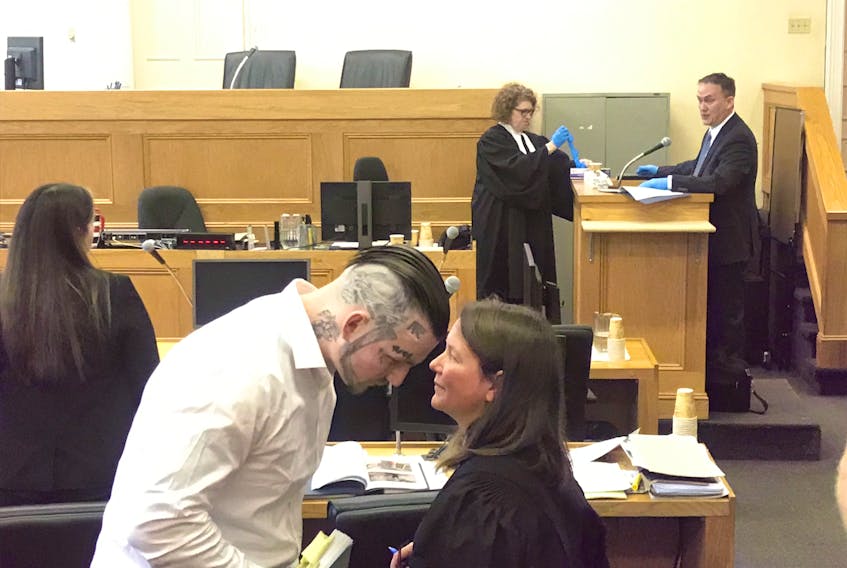 Justin Wiseman speaks to his lawyer, Karen Reyner, during a break in his trial in Newfoundland and Labrador Supreme Court in St. John’s Tuesday. On the witness stand in the background, RNC Const. Pat Hickey, lead investigator in Wiseman’s case, wears the blue nitrile gloves he donned earlier to pick up a piece of evidence - a charred knife - and show it to the court.