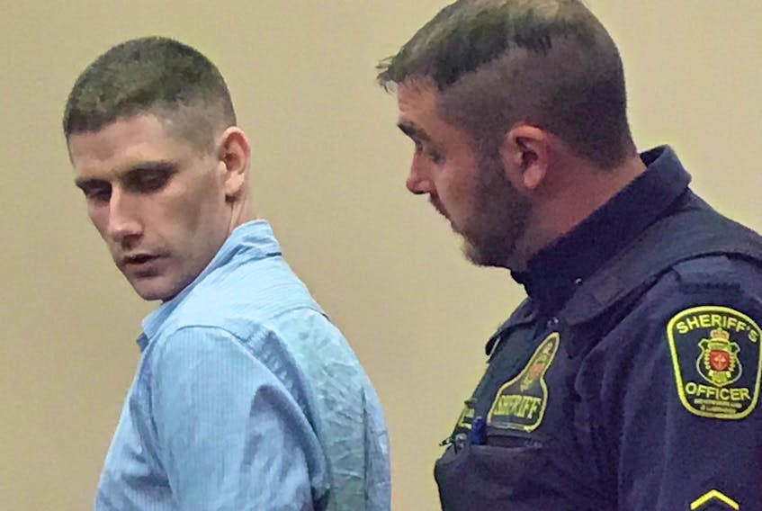 A sheriff handcuffs Andrew Parsons, 28, before escorting him from a courtroom at provincial court in St. John's once his trial wrapped up for the day Monday. Parsons has pleaded not guilty to charges relating to an armed robbery of a Kelligrews convenience store in February.