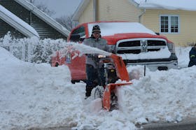 Leonard Constantine clears snow away from the front of his truck on Hamilton Avenue Extension in St. John’s Wednesday.