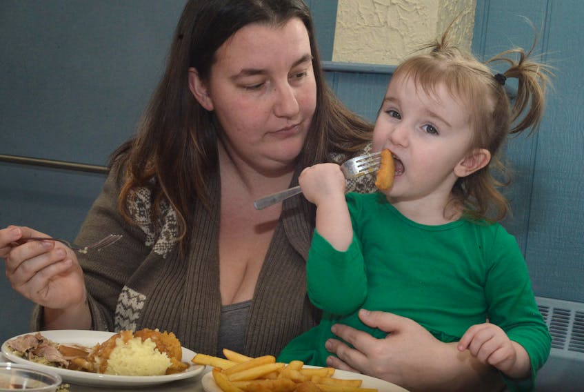 Chrissy Young and her daughter, Maliyah, 2, savour the turkey dinner at the 11th annual Community Christmas Dinner at the Knights of Columbus Hall on St. Clare Avenue in St. John’s Monday afternoon.