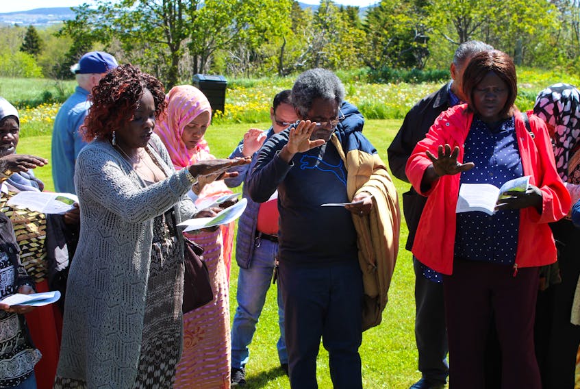 A group of new Canadians celebrate the blessing of the water, flowers and garden at the Mercy Centre of Ecology and Justice on Mount Scio Road in St. John’s.