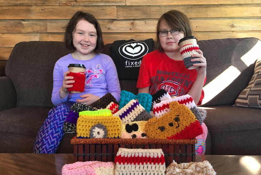 Sisters Lily Healey and Mya Healey, of Grand Falls-Windsor, pose with a basket of donated coffee cozies for their Janeway fundraiser.