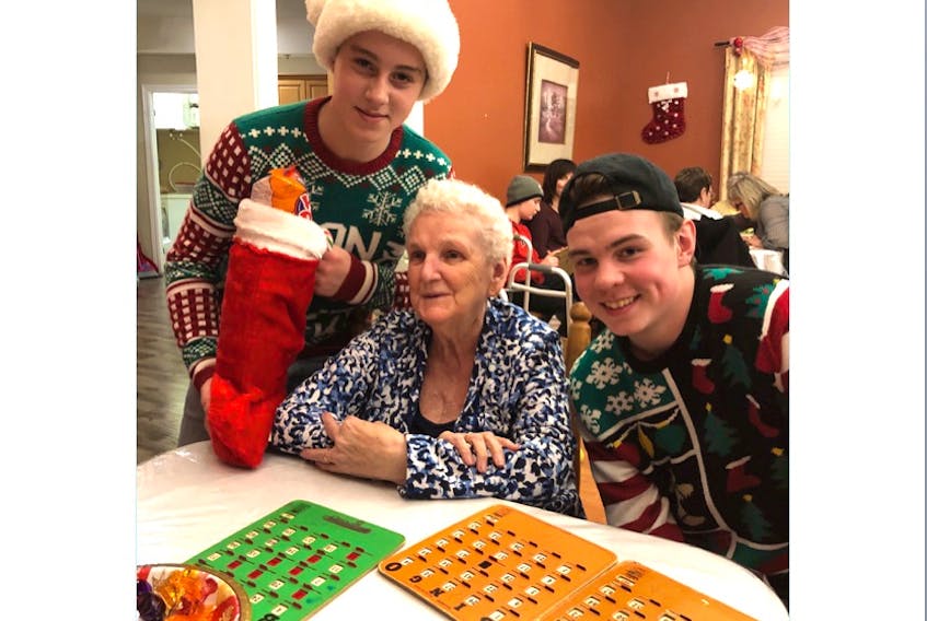Frances Wells, a resident at Alderwood Estates Retirement Home in Witless Bay, played several games of bingo and got a Christmas stocking from members of the Southern Shore Breakers peewee burgundy hockey team recently. Members of the team who dropped by to help the residents celebrate the season were Jaden Putt (left) and Brandon Ennis (right).
