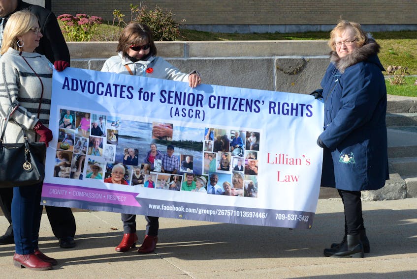 From left, Mary Burt, Sharon Goulding-Collins and Linda Banfield, members of Advocates for Senior Citizens’ Rights, hold a protest sign outside the Confederation Building on Monday.