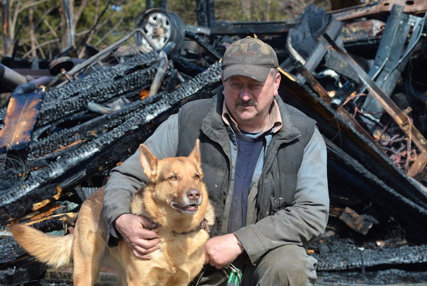 Bob Bennett with Moxxi, a seven-year-old Belgian shepherd mixed breed that likely saved his life Monday afternoon by barking and alerting him to a fire in his garage while he worked underneath a car.