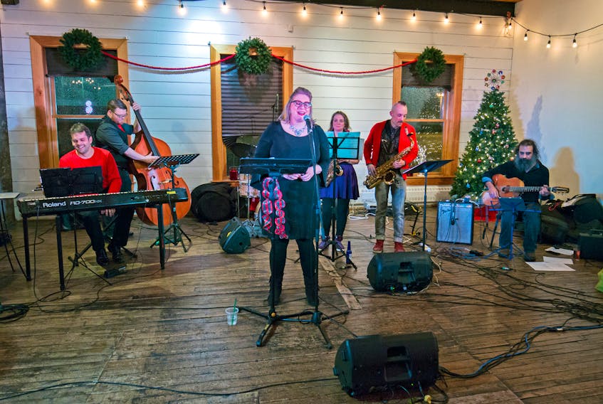 Seven-piece band (L-R: James Hurley (piano), Josh Ward (bass), Kate Hopkins (vocals), Chuck Buckets (drums, obscured), Susan Evoy (sax), Greg Bruce (sax), Duane Andrews (guitar)) performed a stacked set of holiday jazz classics at the Rocket Room on December 18. — Photo by Alick Tsui