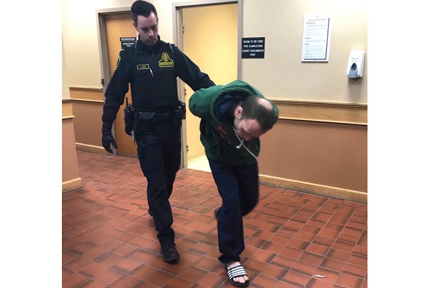 Michael Francis Squires, 40, ducks from reporters' cameras as he is escorted from a provincial courtroom in St. John's Tuesday afternoon.