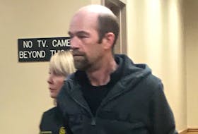 Samuel Caines, 42, is escorted from a St. John's courtroom Wednesday. He and his wife, Melissa Dawe, have been charged alongside two others for allegedly stealing vehicles and selling them for scrap metal.