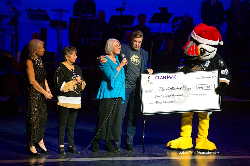 On stage for the presentation, from left: Terri Andrews, director, and Sheilagh Guy Murphy, host, of “Our Divas Do Christmas”, Joann Thompson, director of The Gathering Place, Dean MacDonald and Hockey mascot Buddy the Puffin.