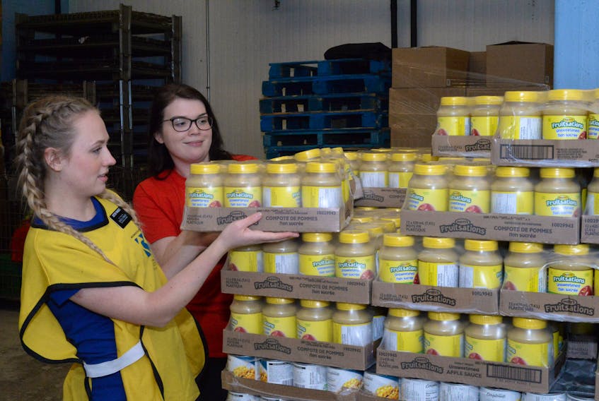 Sister Skylar Rhodes (left) of the Latter-day Saints and Brianna Rogers, a tool technician with Halliburton Group Canada, unload cases of Mott’s Fruitsations at the Community Food Sharing Association warehouse on Wednesday.