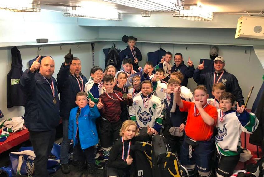 Members of the Paradise Warriors celebrate with their gold medals after beating the Northeast Eagles in the final of the provincial atom F championship Sunday in Glovertown, a game that lasted five overtime periods, or 88 minutes and 11 seconds in total.