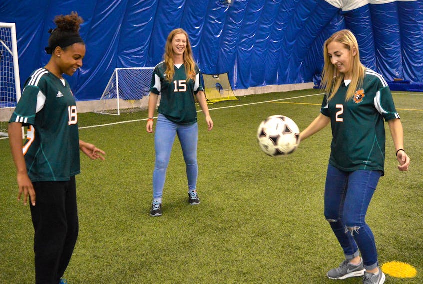 Cape Breton Capers soccer players (from left) Tamara Brown, Robyn Novorolsky and St. John’s native Alyssa Armstrong play around with a soccer ball in Sydney, N.S., on Monday. The Atlantic University Sport champion Capers compete in the national soccer championships in Manitoba later this week. — Photo by the Cape Breton Post