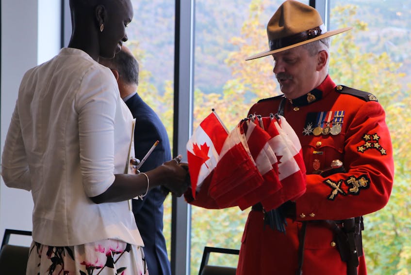 Abuk Angok Tong, 23, originally from South Sudan, accepts congratulations and a Canadian flag from RCMP B Division Sgt. Maj. Doug Pack during a citizenship ceremony Friday at the Emera Innovation Exchange, Signal Hill Campus, Memorial University. Twenty-nine new Canadians from 16 countries received their Canadian citizenship.