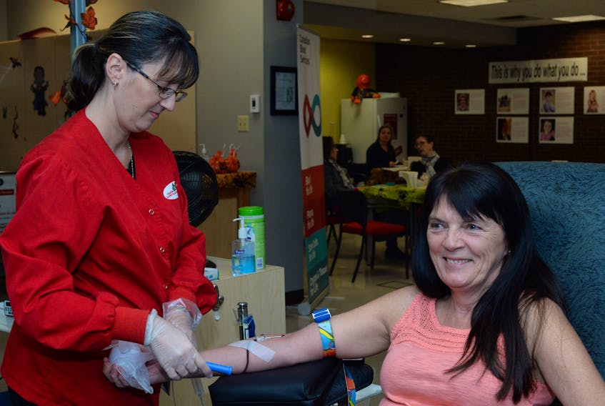 Mary Lynn Menchinton, sales co-ordinator with The Telegram’s advertising sales department, rolled up her sleeve to make her blood donation on Friday morning as she is assisted by Canadian Blood Services staff member Sherry Leaman.