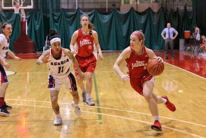 Jane Baird (4) of the Memorial Sea-Hawks moves the ball down the court past Paloma Anderson (11) of the Acadia Axewomen during AUS women’s basketball action at the Field House in St. John’s Sunday. Anderson had 29 points and 10 rebounds as league-leading Acadia defeated Memorial 90-79 for a sweep of a two-game weekend series in St. John’s. See story, page A10.