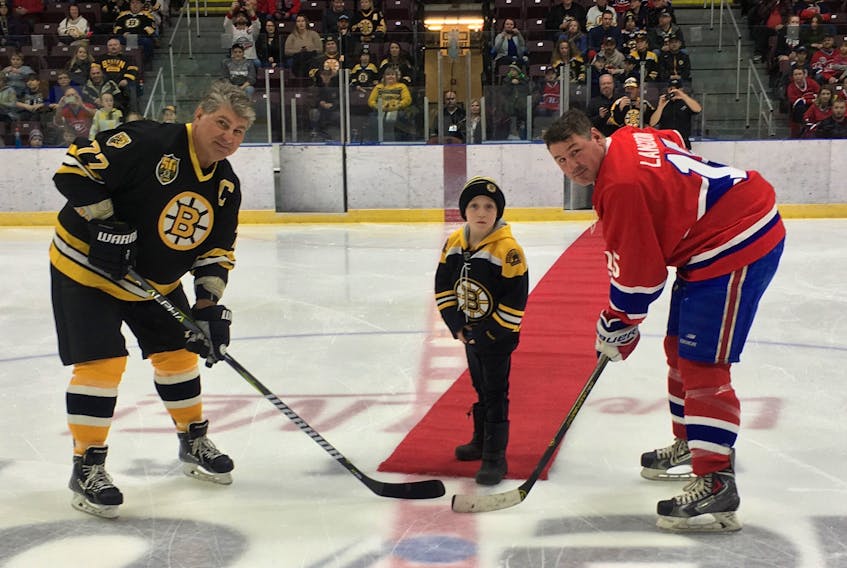Submitted photo — Charlie Druken of Paradise drops the puck for a ceremonial faceoff between the Boston Bruins’ Ray Bourque and Darren Langdon of the Montreal Canadiens during an NHL alumni game at Mile One Centre last week.
