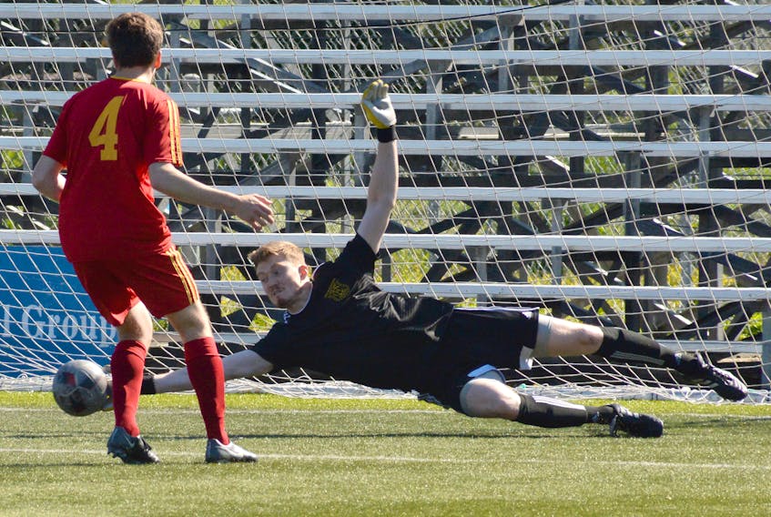 Holy Cross keeper Thomas Pieroway makes a diving save on a shot from the C.B.S. Strikers as teammate Isaac Bonisteel (4) follows up on the play during Challenge Cup soccer action at King George V Park on Sunday.