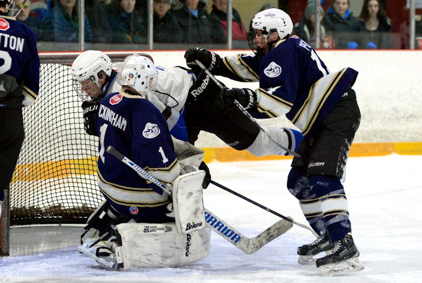 Daniel Penney of the Gonzaga Vikings (right) pushes Michael Gill of the Mount Pearl Senior High Huskies towards the net and Gonzaga goaltender Liam Buckingham during Confederation Cup high school hockey action at the Goulds Arena Sunday afternoon.